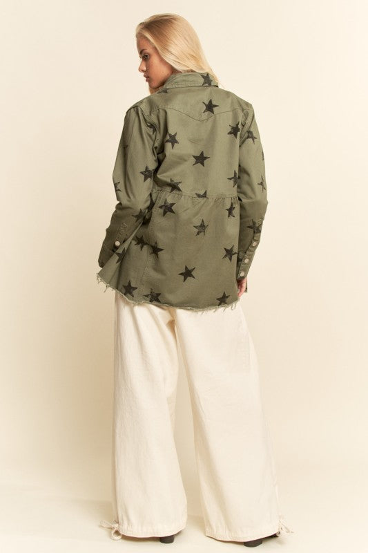 Person wearing a green jacket with star patterns on a plain background