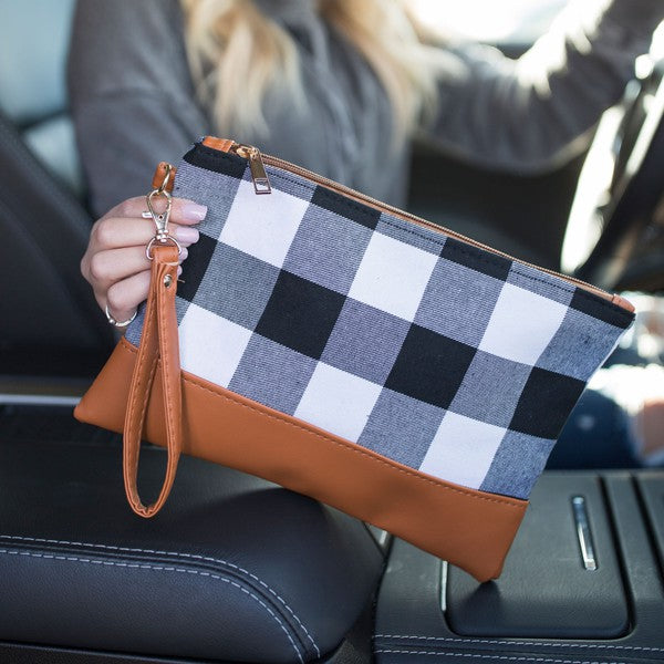 Person holding a checkered pouch with brown trim in a car.