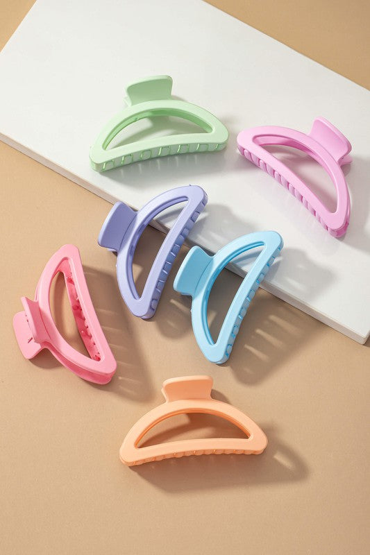 Set of colorful hair clips on a white surface with a beige background