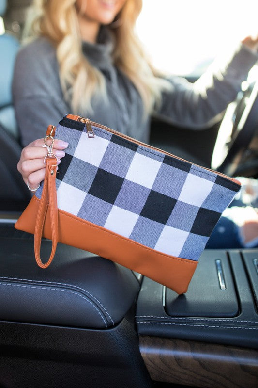 Person holding a checkered clutch with brown accents inside a vehicle