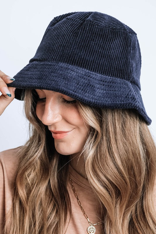 Woman wearing a navy blue bucket hat against a light background