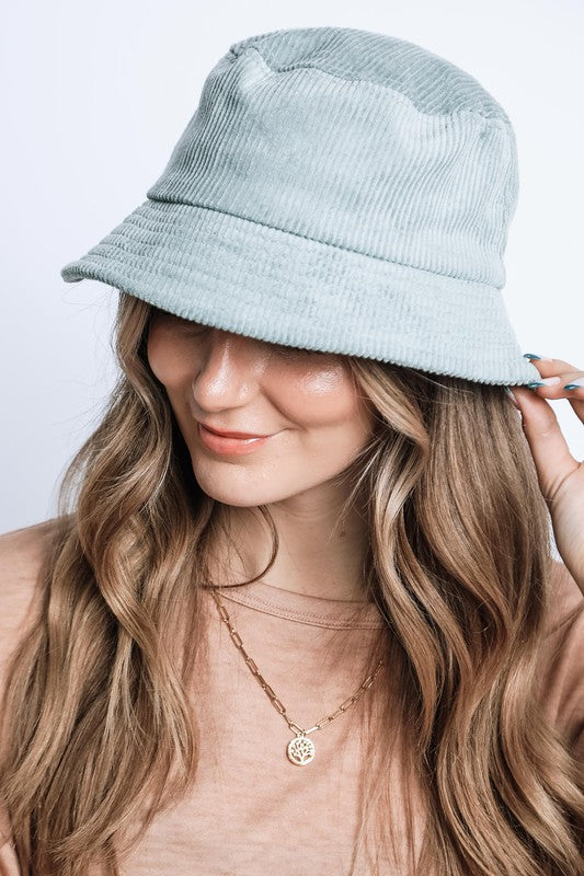Woman wearing a light blue bucket hat against a plain background