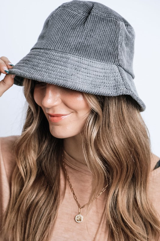 Woman wearing a gray bucket hat with a plain background