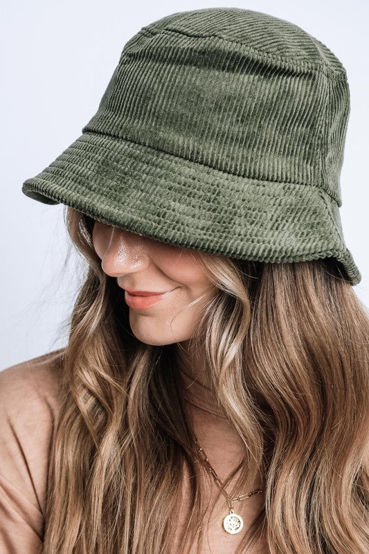 Person wearing a green corduroy bucket hat against a light background