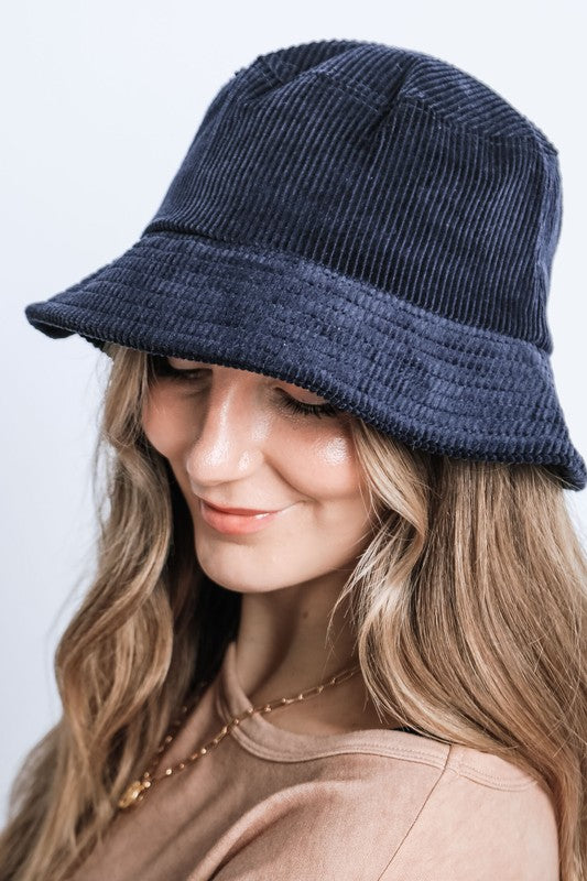 Woman wearing a navy blue bucket hat against a white background