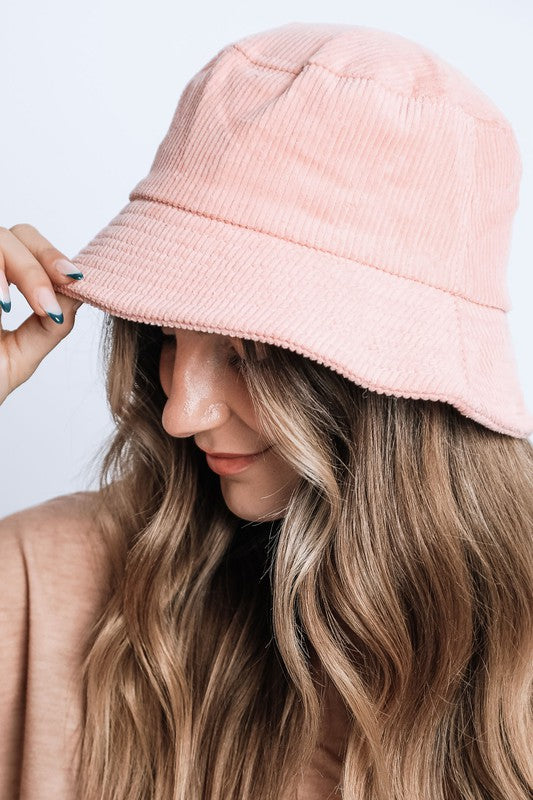 Person wearing a pink bucket hat with a plain background