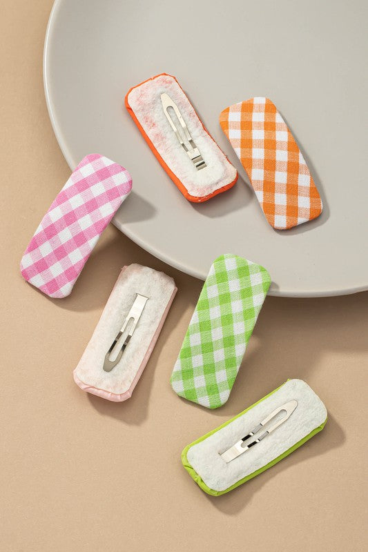 Set of colorful checkered cases with hair clips on a beige background
