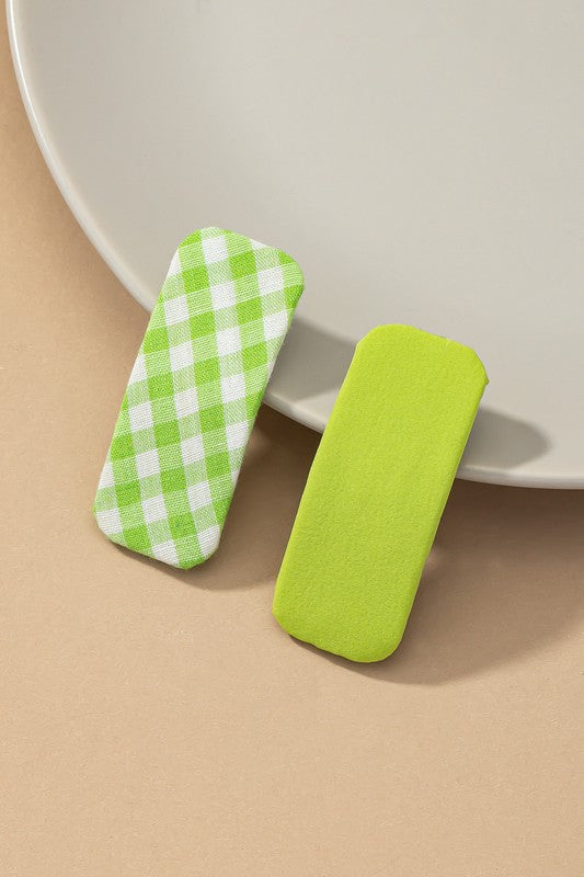 Two green items, one checkered, on a beige surface with a white plate in the background.