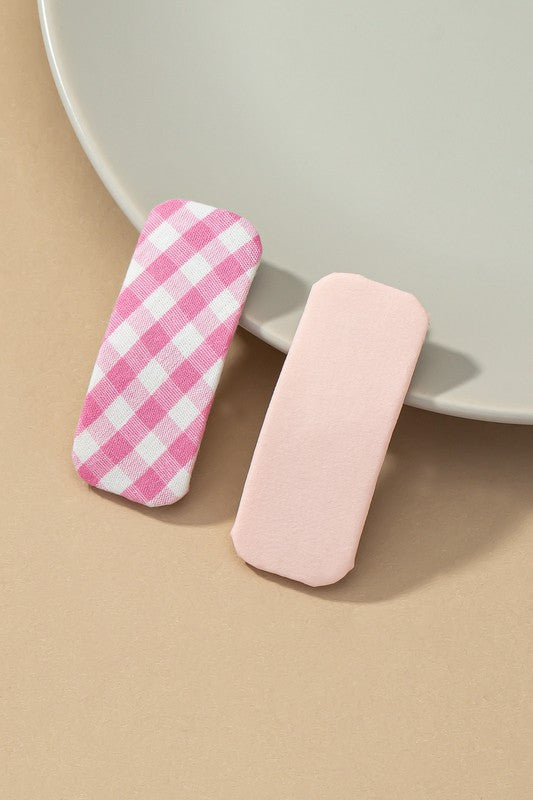 Two pink and white checkered items on a beige surface with a neutral background