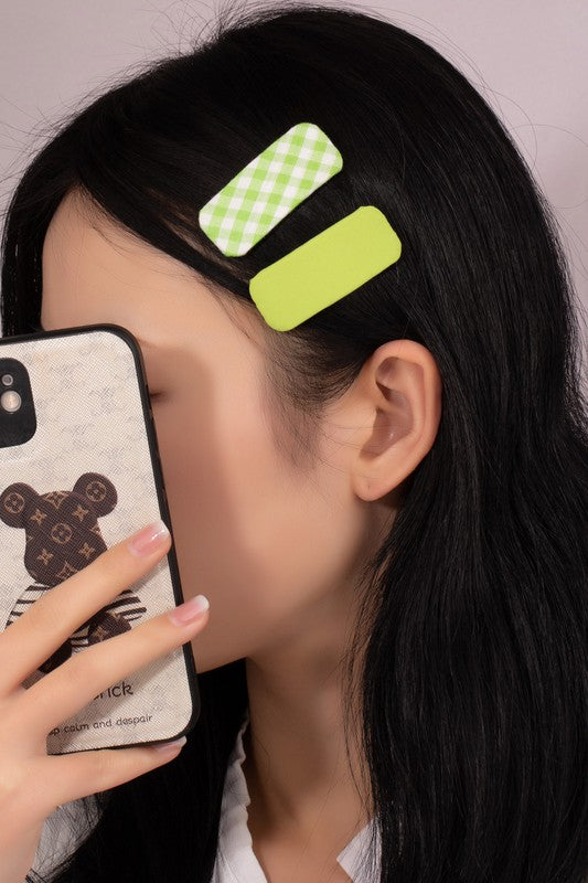 Person with green hair clips holding a phone with a bear design.