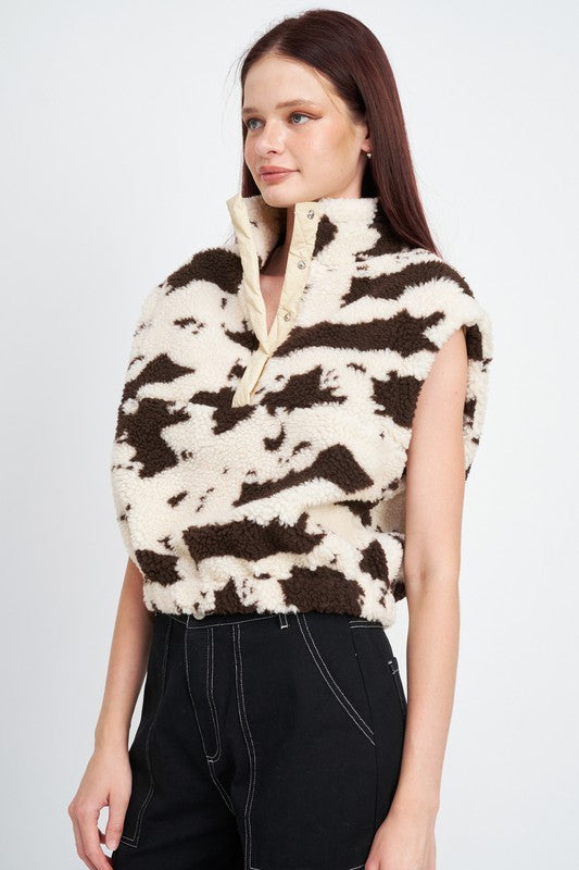 Woman wearing a patterned vest over a plain background