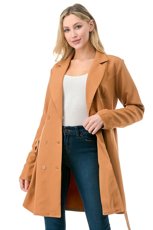 Woman wearing a brown coat over a white top and blue jeans on a white background