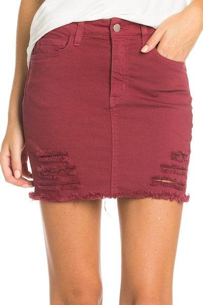 Maroon denim skirt with frayed hem on a white background