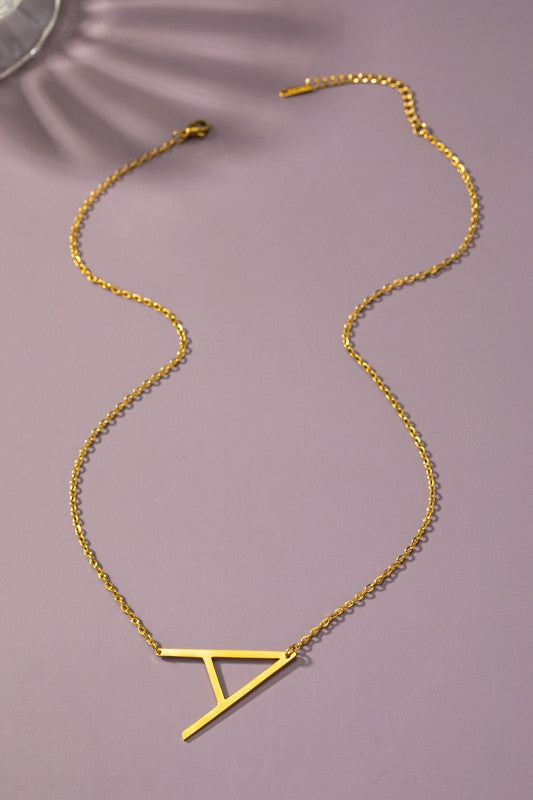 Gold necklace with a triangular pendant on a purple background