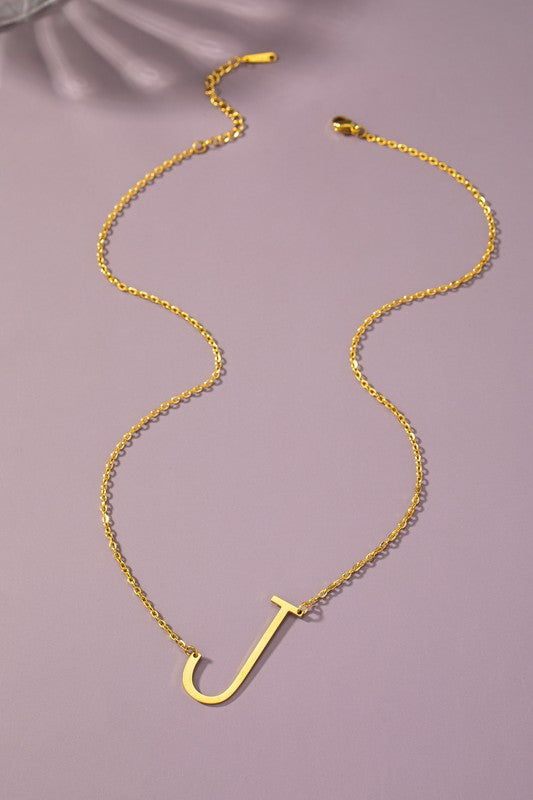 Gold necklace with a 'J' pendant on a purple background