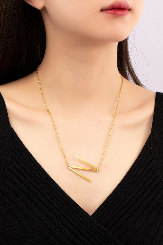 Gold necklace with a unique design worn by a person against a neutral background