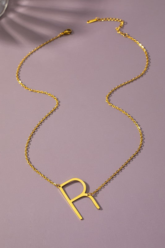 Gold necklace with a 'R' pendant on a purple background