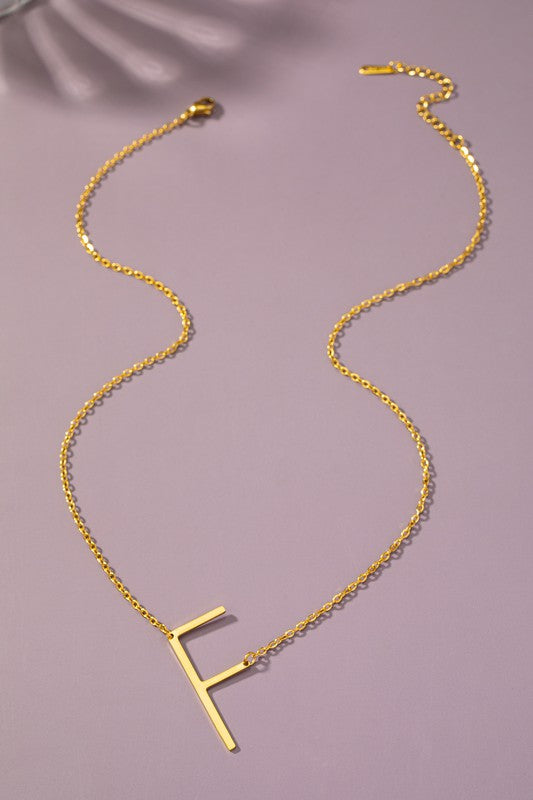 Gold necklace with a letter 'F' pendant on a purple background