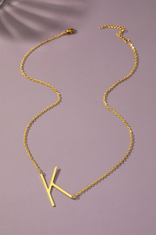Gold necklace with a 'K' pendant on a purple background