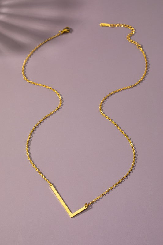 Gold necklace with a V-shaped pendant on a purple background