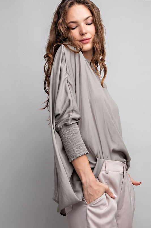 Woman wearing a light gray outfit against a plain background