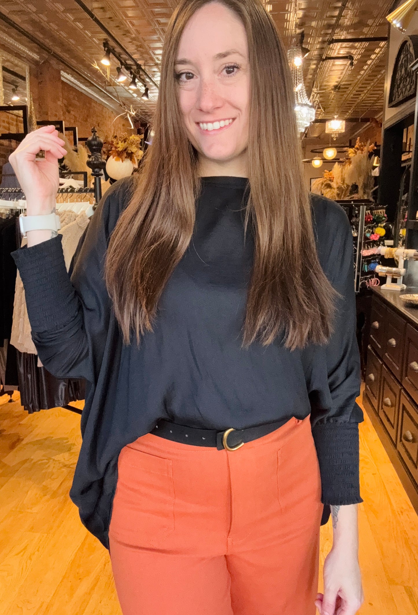 Woman wearing a black top and orange pants in a store setting
