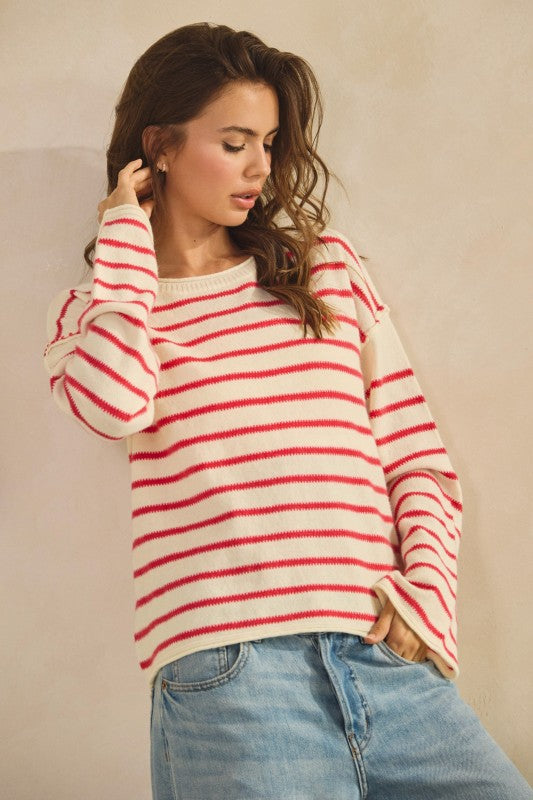 Woman wearing a red and white striped sweater with blue jeans against a plain background