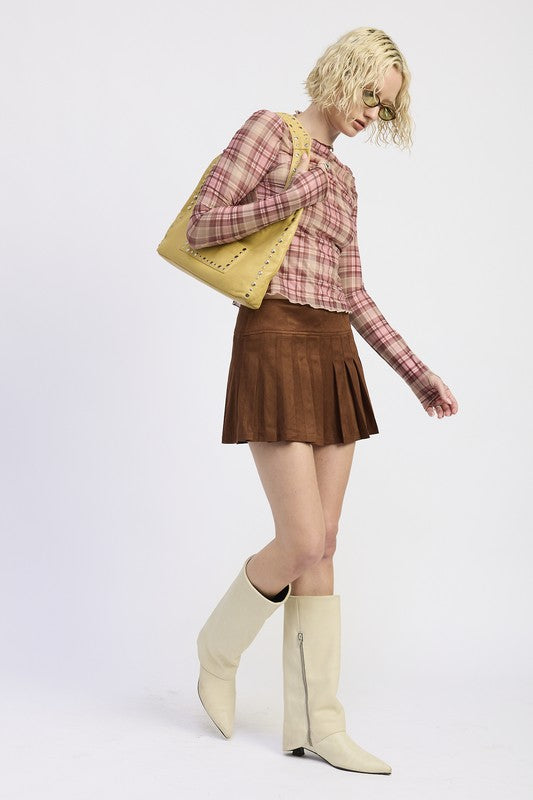 Woman wearing a plaid shirt and brown skirt with a yellow bag on a white background