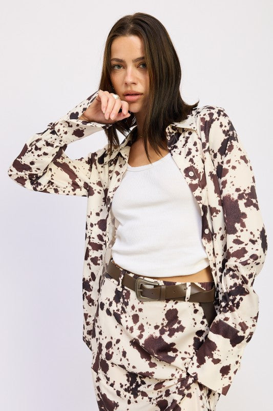 Woman wearing a patterned shirt and pants with a white background