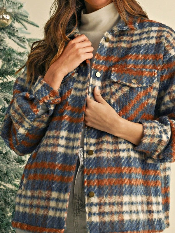 Person wearing a plaid jacket with blue, orange, and beige colors against a Christmas tree background.