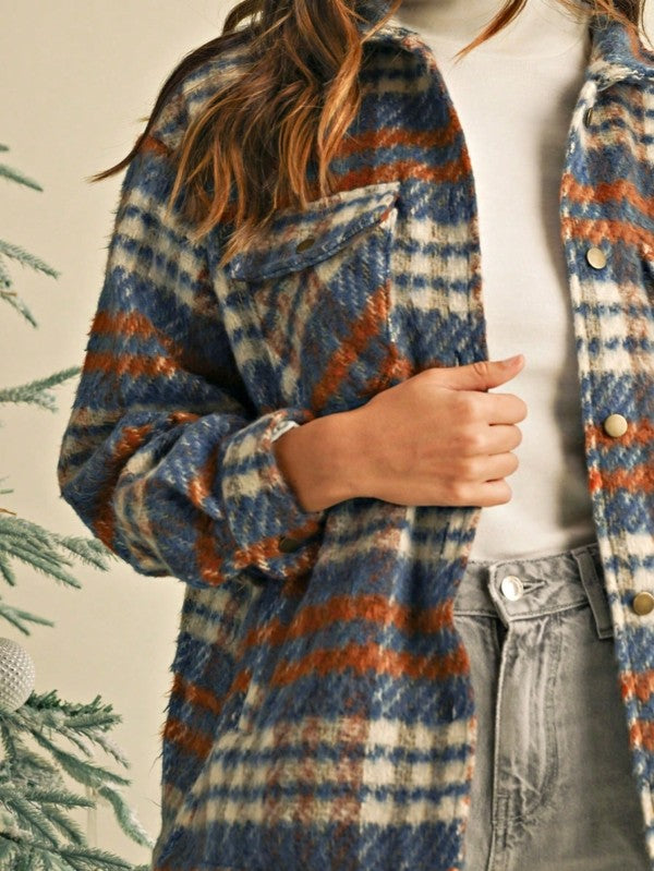 Person wearing a plaid coat with blue, orange, and beige colors, standing against a neutral background.