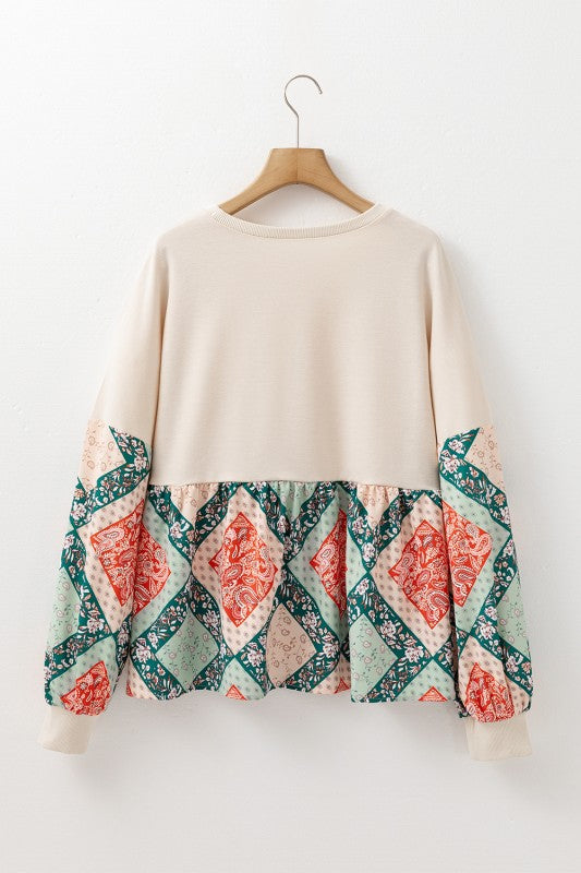 Beige sweater with patterned sleeves on a wooden hanger against a white background