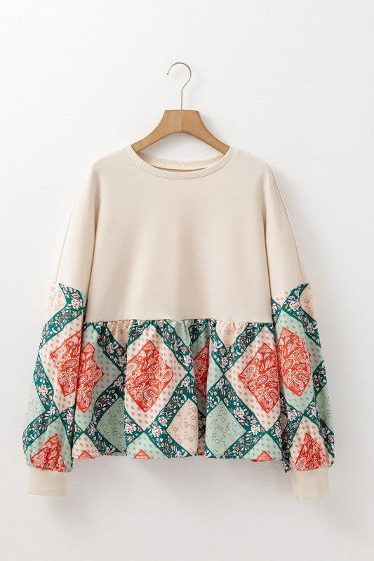 Beige sweater with patterned sleeves on a wooden hanger against a white background