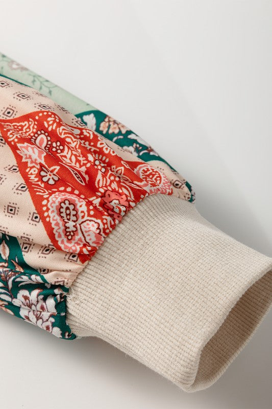 Folded fabric with colorful pattern and beige fabric underneath on a light gray background