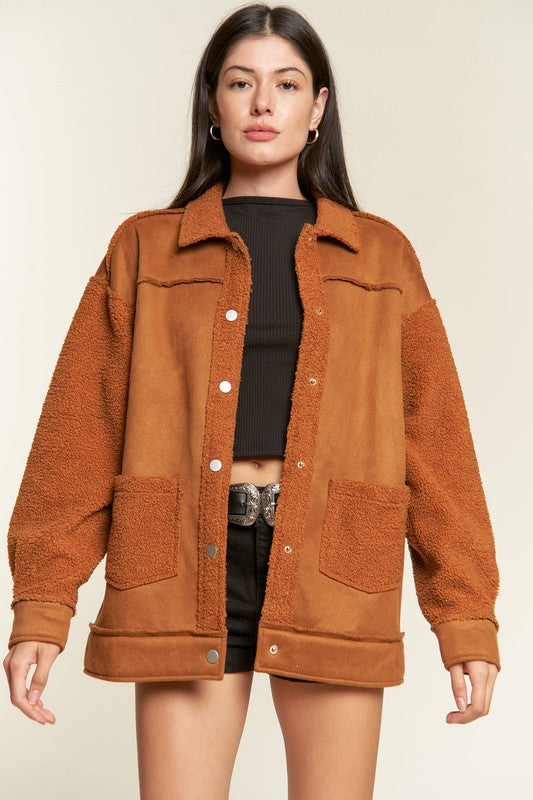 Woman wearing a brown jacket over a black outfit on a beige background