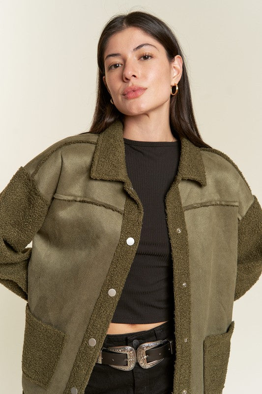 Woman wearing an olive green jacket over a black top on a beige background
