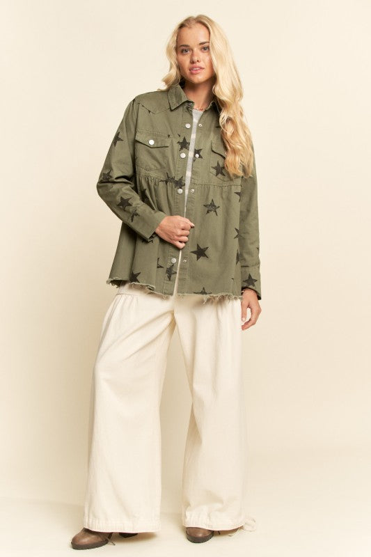 Woman wearing a green jacket with star patterns and white pants on a beige background