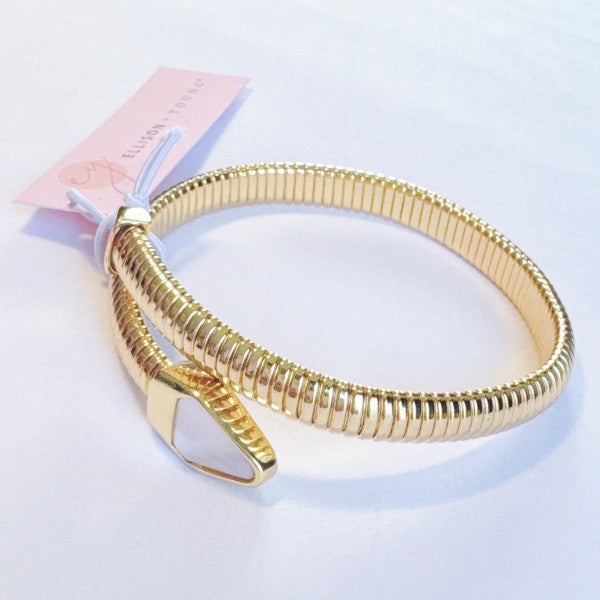 Gold bracelet on a light blue background with a pink tag.