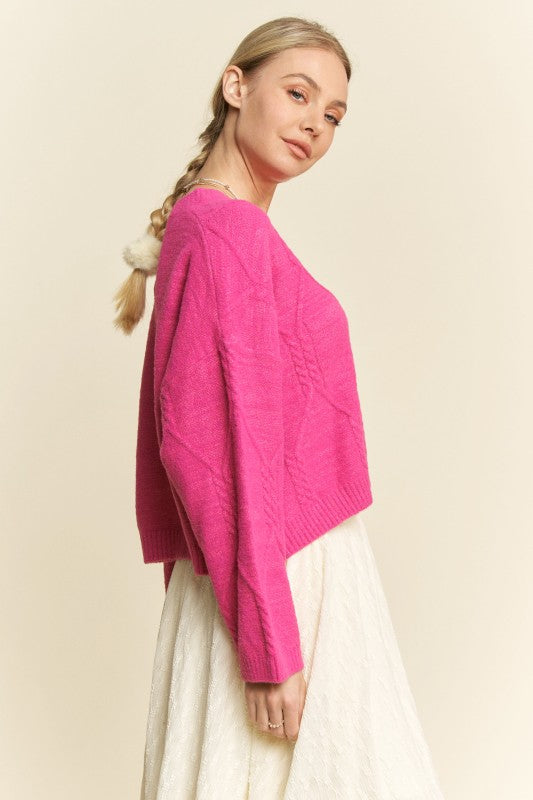 Woman wearing a bright pink sweater and white pants on a beige background