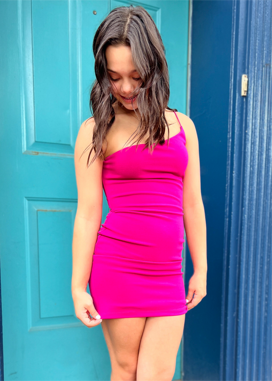 Woman wearing a bright pink dress standing in front of a blue door.