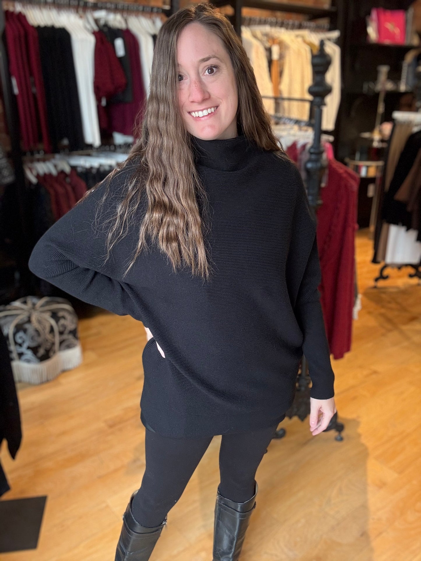 Woman wearing a black turtleneck sweater and leggings in a clothing store.
