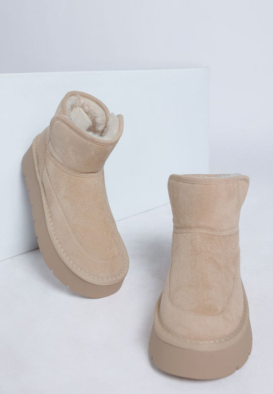 Pair of beige suede boots on a white background