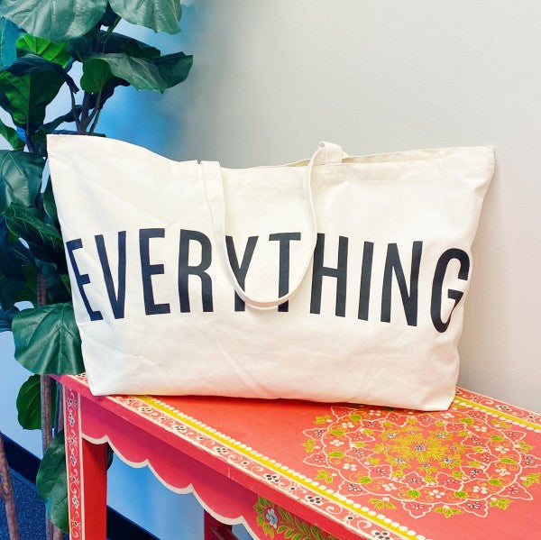 Beige tote bag with 'EVERYTHING' text on a colorful table