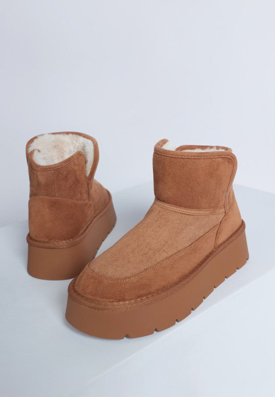 Pair of brown suede platform boots with white fur lining on a light gray background