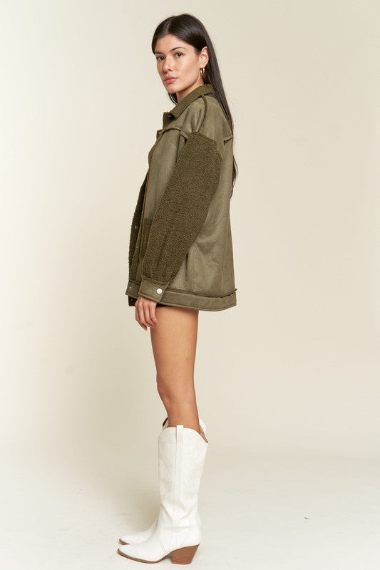 Woman wearing an olive green jacket and white cowboy boots on a beige background