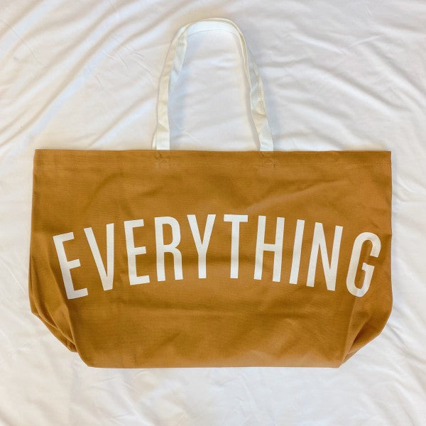 Brown tote bag with 'EVERYTHING' printed on it, lying on a white surface.