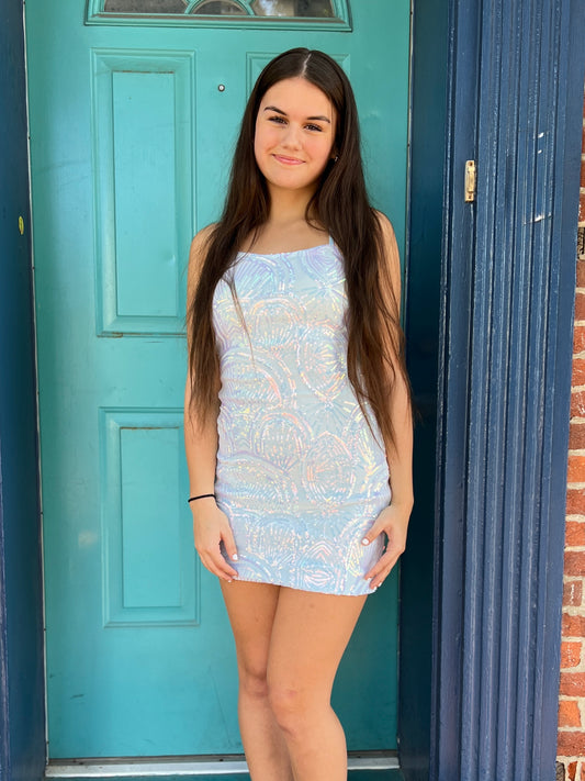 Woman in a light blue dress standing in front of a teal door.