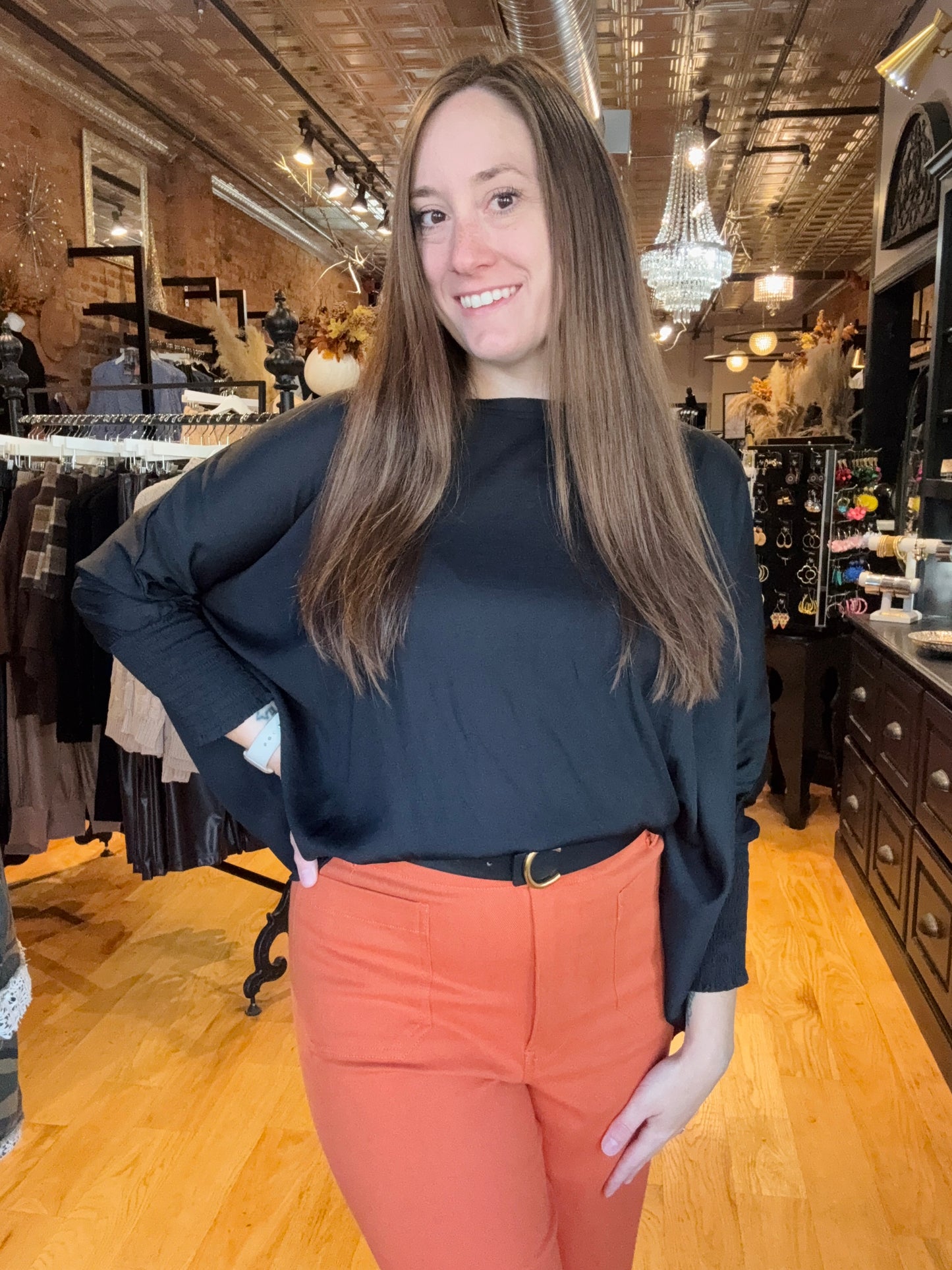 Woman in a store wearing a black top and orange pants