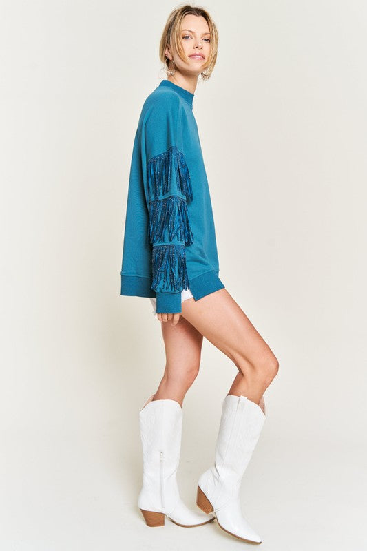 Woman wearing a blue dress with fringe details and white cowboy boots on a plain background