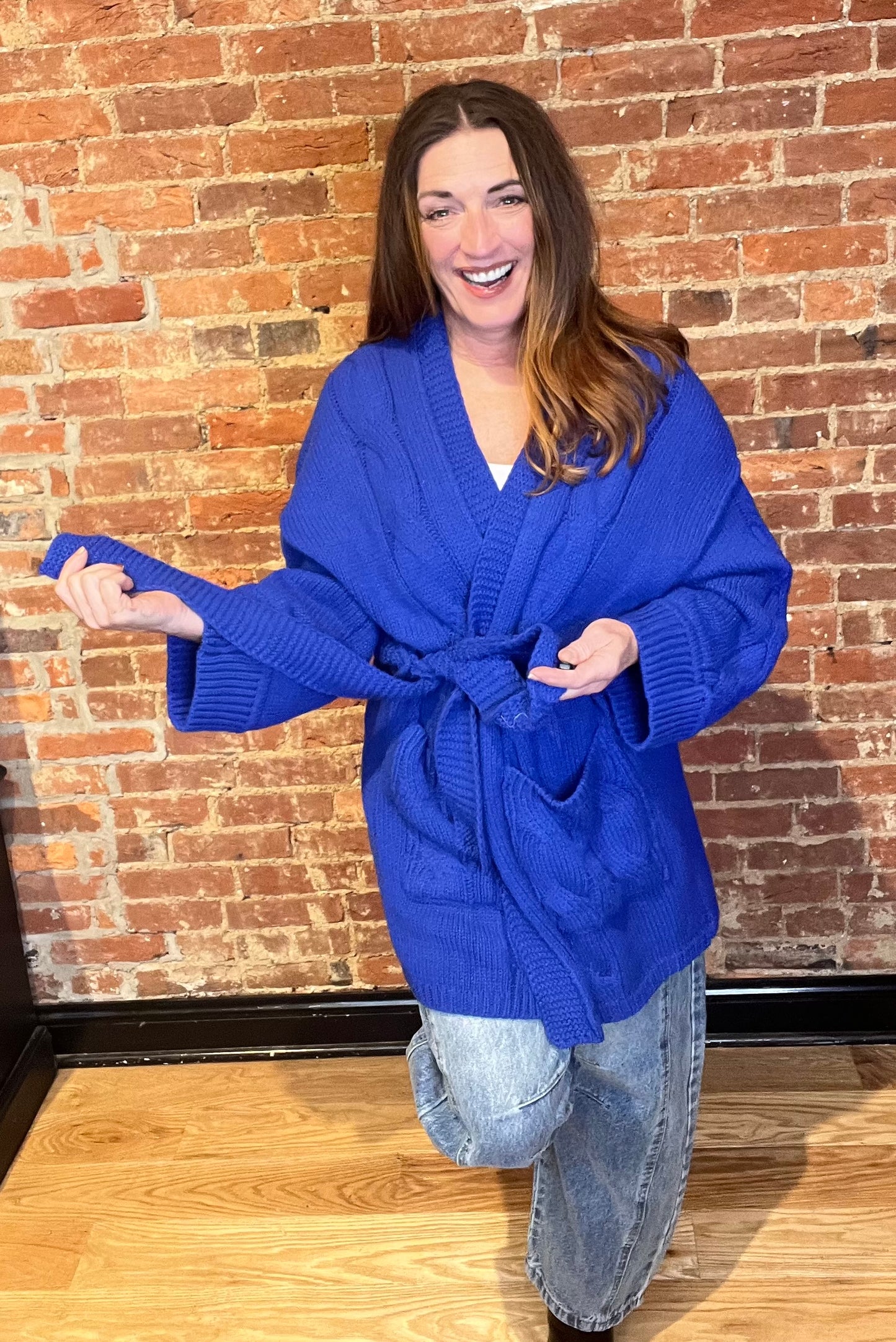 Blue cardigan sweater, relaxed fit, dropped shoulders, long sleeves, open front with waist tie wrap, pockets, kimono silhouette.
